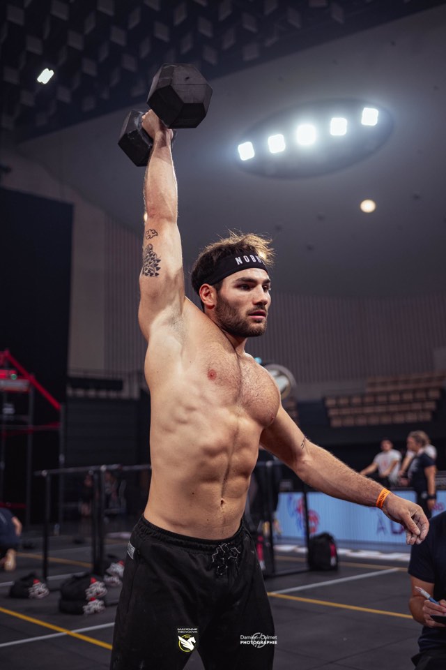 Clément Riallin tient un haltère à bout de bras au-dessus de la tête, en compétition